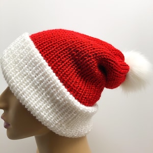 May include: A red and white knitted Santa hat with a white pom-pom. The hat features a classic design with a red crown and a white brim. The pom-pom is on the end of the hat. This festive hat is perfect for holiday celebrations.