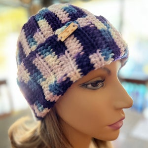 May include: A purple, white, and blue crocheted beanie with a wooden tag that says "Made by Cathy".