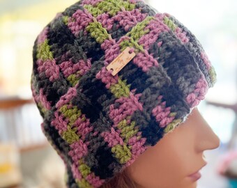 May include: A crocheted beanie hat in black, green, and pink with a small brown leather tag that says "The Knotty Knitter".
