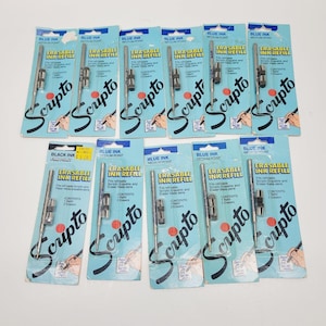 May include: A collection of Scripto erasable ink refills in blue and black. Each package contains a refill and two erasers. The packaging is light blue with the Scripto logo and product information.