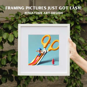 May include: A white picture frame with a blue background and a yellow pair of scissors with a small figure sliding down the blade. The text "FRAMING PICTURES JUST GOT EASY! MINIATURE ART DESIGN" is at the top of the frame.