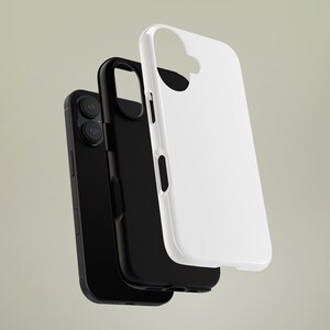 May include: A black smartphone with a black phone case and a white phone case. The phone has two camera lenses. The cases are designed to protect the phone from damage.