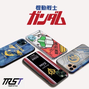 Könnte beinhalten: Eine Auswahl an Handyhüllen mit Designs aus der Anime-Serie "Mobile Suit Gundam". Die Hüllen zeigen verschiedene Grafiken, darunter Text und Illustrationen, in Farben wie Blau, Rot und Gelb. Sie sind auf einem weißen Hintergrund angeordnet.