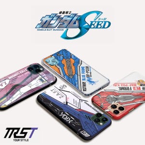 Puede incluir: Varias fundas para teléfonos con diseños coloridos y texto, incluyendo "MOBILE SUIT GUNDAM" y "ASTRAY BLUE FRAME." Las fundas presentan patrones en azul, rojo, blanco y morado.