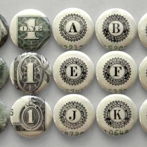 May include: Twelve round buttons featuring images of US currency, including a portrait of George Washington, the Great Seal of the United States, the pyramid on the back of a dollar bill, and the words "ONE" and "Federal Reserve" with letters A through L.