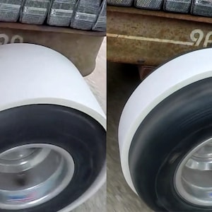 May include: Two white-walled tires with black tread and silver rims. The tires are mounted on a vehicle with a rusty metal frame. The number "90" is visible on the frame.