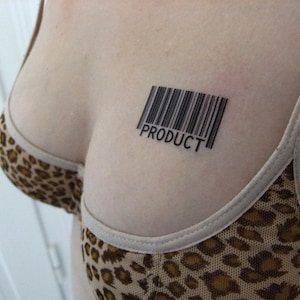 Pu&ograve; includere: Primo piano del petto di una persona con un tatuaggio a codice a barre che recita "PRODUCT". La persona indossa un reggiseno con stampa leopardata.