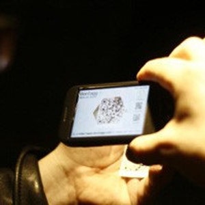 Puede incluir: Una persona usando un tel&eacute;fono inteligente para escanear un c&oacute;digo de barras en una tarjeta blanca. El c&oacute;digo de barras es blanco y negro y tiene el texto "WWW.FANDANGO.COM" impreso debajo.