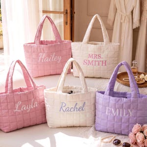 Peut inclure: Cinq sacs fourre-tout matelassés aux couleurs pastel, notamment rose, blanc et lavande. Chaque sac possède deux anses et un nom ou titre personnalisé brodé sur le devant en lettres cursives ou en lettres capitales : Hailey, Mrs. Smith, Layla, Rachel et Emily.