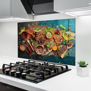 Könnte beinhalten: Eine farbenfrohe Küchenrückwand mit einer Auswahl an Gewürzen und Kräutern. Das Bild zeigt verschiedene Gewürze in kleinen Holzschalen, zusammen mit Holzlöffeln, Zimtstangen und Sternanis. Die Farbpalette umfasst Rot-, Grün-, Gelb- und Brauntöne.