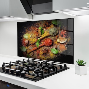 Peut inclure: Gros plan sur une crédence de cuisine décorative présentant un assortiment d'épices. Deux cuillères en bois sont remplies d'épices rouges et vertes, entourées de feuilles de laurier, d'anis étoilé et d'autres assaisonnements. La palette de couleurs comprend des nuances de rouge, de vert, de jaune et de marron.