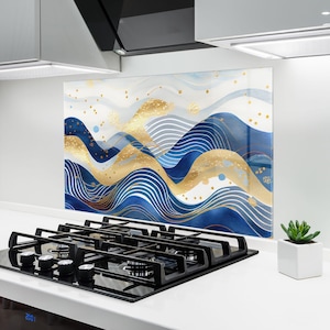 Könnte beinhalten: Eine rechteckige Küchenrückwand mit einem abstrakten Design aus fließenden blauen und weißen Wellen, akzentuiert durch goldene Linien und verstreute goldene Punkte. Das Kunstwerk zeigt ein geschichtetes, rhythmisches Muster aus geschwungenen Linien.