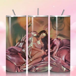 May include: Three stainless steel tumblers with a pink and white design featuring a woman in a pink satin dress. The tumblers have a silver lid and a straw.