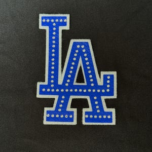 May include: Blue and white felt LA letters with rhinestones.
