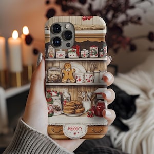 May include: A phone case featuring a detailed illustration of a kitchen shelf with Christmas-themed decorations. The shelf is filled with jars, mugs, and a gingerbread man. The word "MERRY" is displayed on the bottom. The case has a warm, inviting color palette.