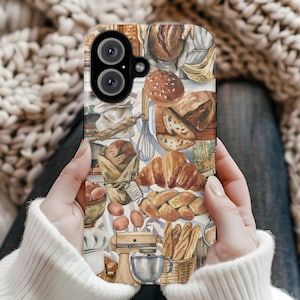 May include: A phone case featuring a watercolor illustration of various baked goods, including bread, croissants, and baguettes. The design incorporates a neutral color palette with elements like a stand mixer, eggs, and a whisk, evoking a bakery theme.