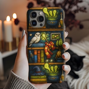 May include: A phone case featuring a whimsical design with a bookshelf theme. The case showcases a white owl, a red and gold scarf, a witch's hat, and a bubbling cauldron. The case has a dark blue background with gold accents.
