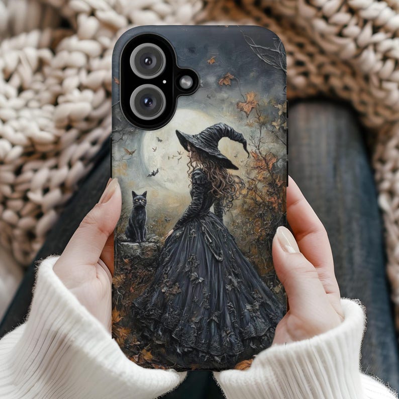 May include: A black phone case with a dark fantasy illustration of a witch in a black dress and hat, standing in a forest with a black cat. The background is a dark forest with a full moon.