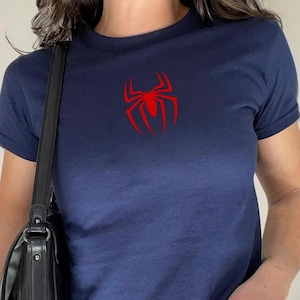 May include: Navy blue t-shirt with a red spider logo on the chest. The shirt has short sleeves and a crew neck. The text "Solid Navy Blend" is in a white oval at the bottom.