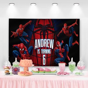 以下が含まれることがあります： スパイダーマンのイラストと「ANDREW IS TURNING 6」の文字が入った誕生日バナー。背景は黒と赤です。パーティーテーブルには、ピンクのテーブルクロス、カップケーキ、お菓子が飾られています。
