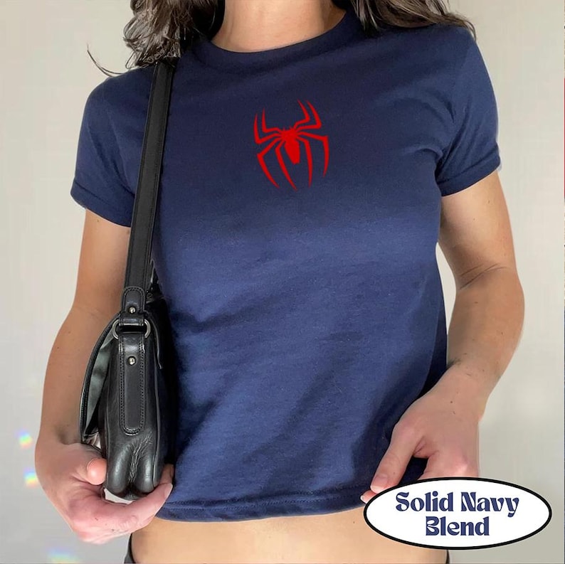 May include: Navy blue t-shirt with a red spider logo on the chest. The shirt has short sleeves and a crew neck. The text "Solid Navy Blend" is in a white oval at the bottom.