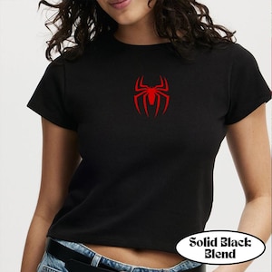 May include: Black crop top with a red spider emblem on the chest. The shirt has short sleeves and a crew neck. The text "Solid Black Blend" is in a white oval at the bottom.