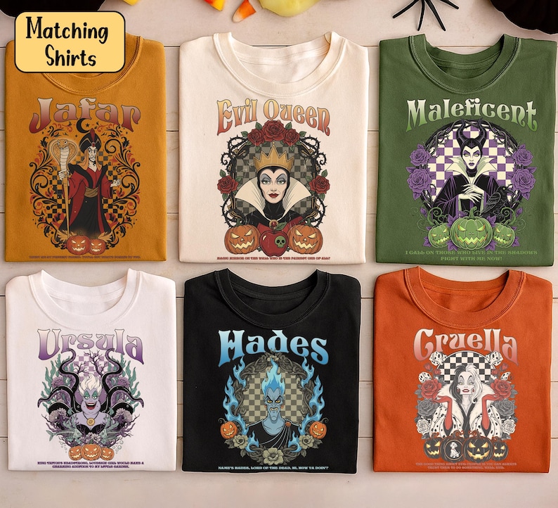 May include: Six Halloween-themed t-shirts are displayed. Each shirt showcases a different Disney villain: Jafar, Evil Queen, Maleficent, Ursula, Hades, and Cruella. The shirts are in various colours, with detailed graphic designs and text.