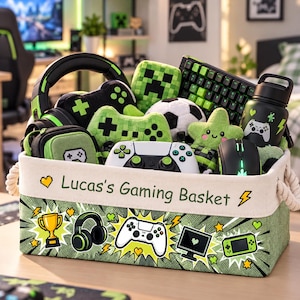 May include: A rectangular fabric storage basket with rope handles, printed with the text 'Lucas's Gaming Basket' and gaming icons. It is filled with green and black gaming accessories, including a headset, plush toys, a keyboard, a mouse, and a controller.