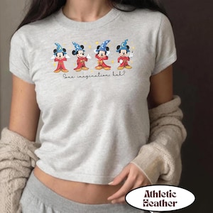 May include: Athletic heather gray t-shirt featuring four cartoon Mickey Mouse characters dressed as sorcerers. Each character wears a blue hat and red robe. The text "Some imaginations, huh?" is printed below the characters.