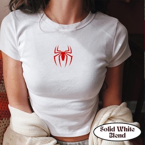 May include: White t-shirt with a red spider graphic. The shirt has short sleeves and a crew neck. The text "Solid White Blend" is in a white oval on the bottom right.