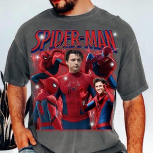 May include: Gray t-shirt featuring a graphic of Spider-Man in various poses, with the text "SPIDER-MAN Peter Parker" in red and blue. The design includes images of the character in his iconic red and blue suit, with lightning bolt accents.