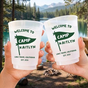 May include: Two translucent plastic cups featuring dark green text that reads WELCOME TO CAMP KAITLYN, with a pennant graphic, followed by LAKE TAHOE, CALIFORNIA and EST. 2026. The cups have a simple, cylindrical design with a slightly flared rim.