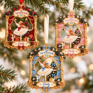 Peut inclure: Trois décorations de Noël représentant une ballerine en robe blanche tenant un casse-noisette. Chaque ornement possède un cadre doré, un sapin, des cadeaux et le texte THE NUTCRACKER 2026 avec le prénom Emily inscrit en bas.
