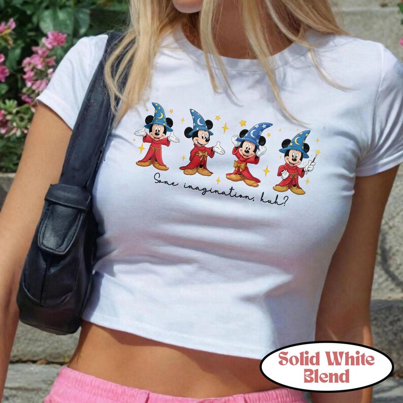May include: White crop top featuring a graphic of Mickey Mouse dressed as a wizard, with the text "Some imagination, huh?" and "Solid White Blend". The cartoon Mickey Mouse is wearing a blue wizard hat and red robes.