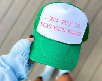 May include: A green and white trucker hat with the text "I only talk to boys with boats" in pink lettering.