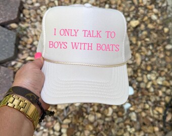 May include: A white trucker hat with a pink embroidered message that reads "I only talk to boys with boats".