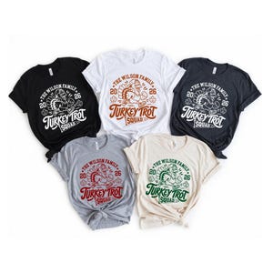 a collection of five T-shirts, each with a unique design and color, arranged in a row.