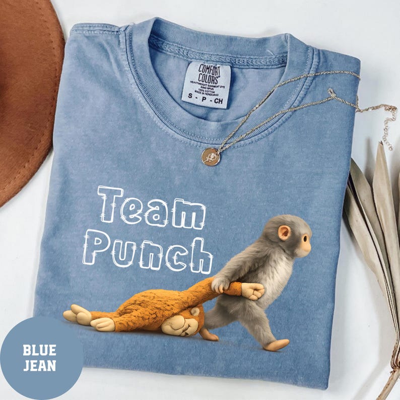 A blue t-shirt with a cartoon image of a monkey holding a stuffed animal, along with the text "Team Punch" printed on it.
