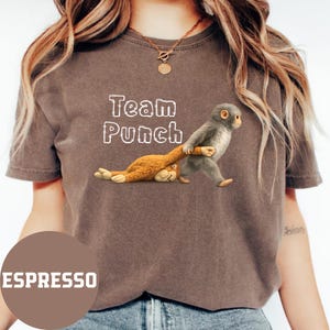 A woman wearing a brown t-shirt with a graphic of a monkey and the text "Team Punch" printed on it.