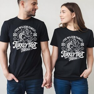 A man and a woman are standing next to each other, both wearing black t-shirts with white text and graphics.