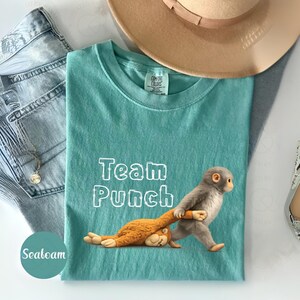 a turquoise t-shirt with a cartoon monkey and the text "Team Punch" printed on it, along with a hat and some jeans.