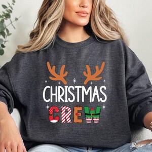 cute christmas crew sweatshirt with reindeer antlers and personalized sleeve name option, matching holiday family sweater for kids and adults, custom christmas shirt for winter celebrations, cozy xmas crew top with festive lettering, personalized holiday gift sweatshirt, christmas pajamas top for family photos, fun reindeer themed christmas sweater, holiday party outfit idea, custom name christmas crew shirt, adorable winter sweatshirt for holiday season