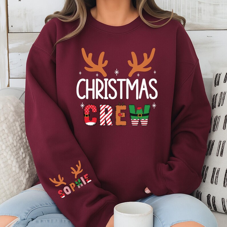 cute christmas crew sweatshirt with reindeer antlers and personalized sleeve name option, matching holiday family sweater for kids and adults, custom christmas shirt for winter celebrations, cozy xmas crew top with festive lettering, personalized holiday gift sweatshirt, christmas pajamas top for family photos, fun reindeer themed christmas sweater, holiday party outfit idea, custom name christmas crew shirt, adorable winter sweatshirt for holiday season