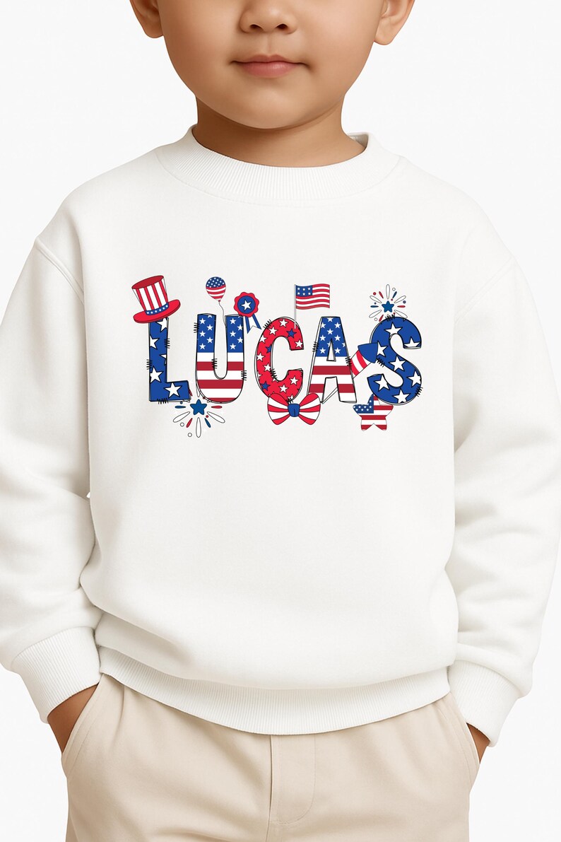 A close-up mockup shows the front of a white kids sweatshirt with the personalized name Lucas printed in large patriotic lettering. The custom design combines red, white, and blue colors, stars, stripes, fireworks, and festive Americana details that make it ideal for Independence Day and the 250th anniversary of the United States. This image clearly highlights the print placement, design scale, and personalized name option for boys or girls.