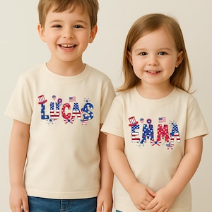 Two smiling children model matching white personalized patriotic T-shirts, one with the custom name Emma and the other with the custom name Lucas. The names are printed in bold red, white, and blue lettering with stars, stripes, fireworks, a patriotic bow, and festive American-themed details. This matching sibling mockup highlights a customizable Fourth of July design created for kids, toddlers, and family celebration outfits honoring America’s 250th birthday.