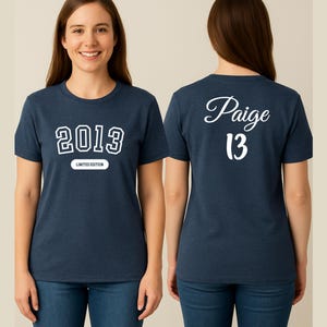 A woman wearing a navy blue t-shirt with the text "2013" and " Paige 13" printed on it, smiling at the camera.