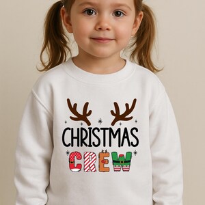cute christmas crew sweatshirt with reindeer antlers and personalized sleeve name option, matching holiday family sweater for kids and adults, custom christmas shirt for winter celebrations, cozy xmas crew top with festive lettering, personalized holiday gift sweatshirt, christmas pajamas top for family photos, fun reindeer themed christmas sweater, holiday party outfit idea, custom name christmas crew shirt, adorable winter sweatshirt for holiday season