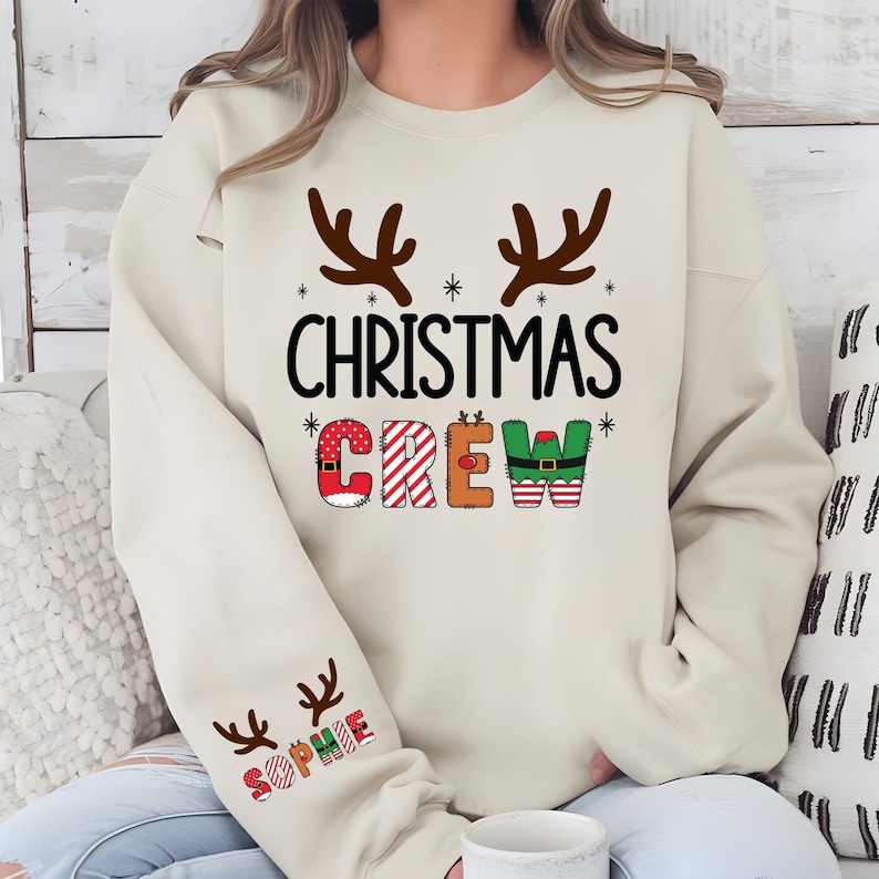 cute christmas crew sweatshirt with reindeer antlers and personalized sleeve name option, matching holiday family sweater for kids and adults, custom christmas shirt for winter celebrations, cozy xmas crew top with festive lettering, personalized holiday gift sweatshirt, christmas pajamas top for family photos, fun reindeer themed christmas sweater, holiday party outfit idea, custom name christmas crew shirt, adorable winter sweatshirt for holiday season