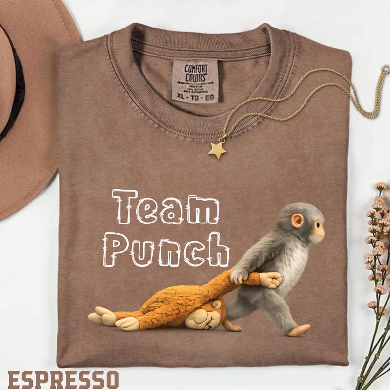 a brown t-shirt with a cartoon image of a monkey holding a stuffed animal, along with the text "Team Punch" printed on it.
