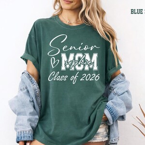 Senior Mom Class of 2026 Comfort Colors® tee in a soft blue jean shade with white personalized graduation design. This custom shirt is a stylish way for moms to celebrate their senior graduate with name personalization, school spirit style and meaningful keepsake details for graduation day, senior night, family photos and parties.